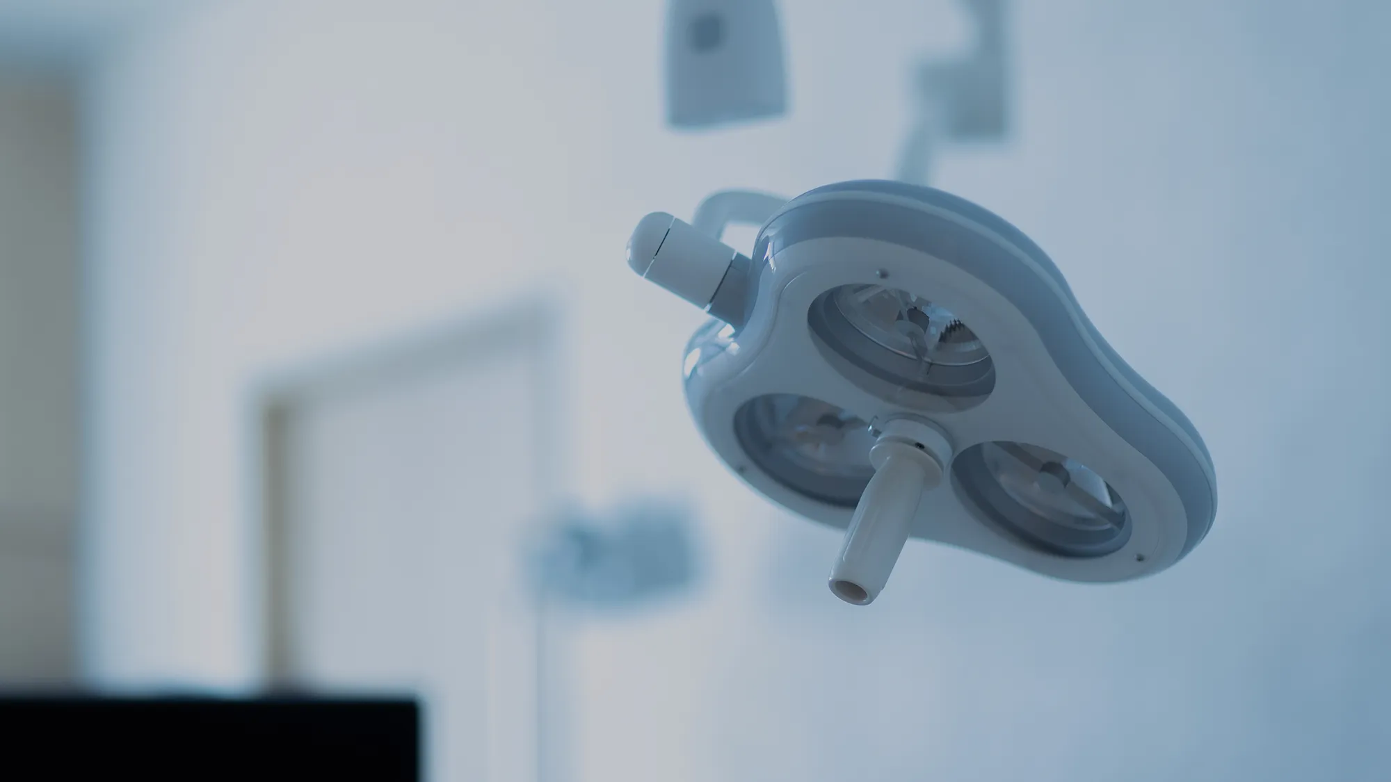 Close-up of a dental surgical light with adjustable arms in a sterile clinic setting