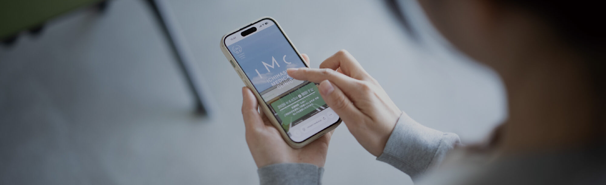 Person holding a smartphone and tapping the screen, showing a medical clinic app open on the display.